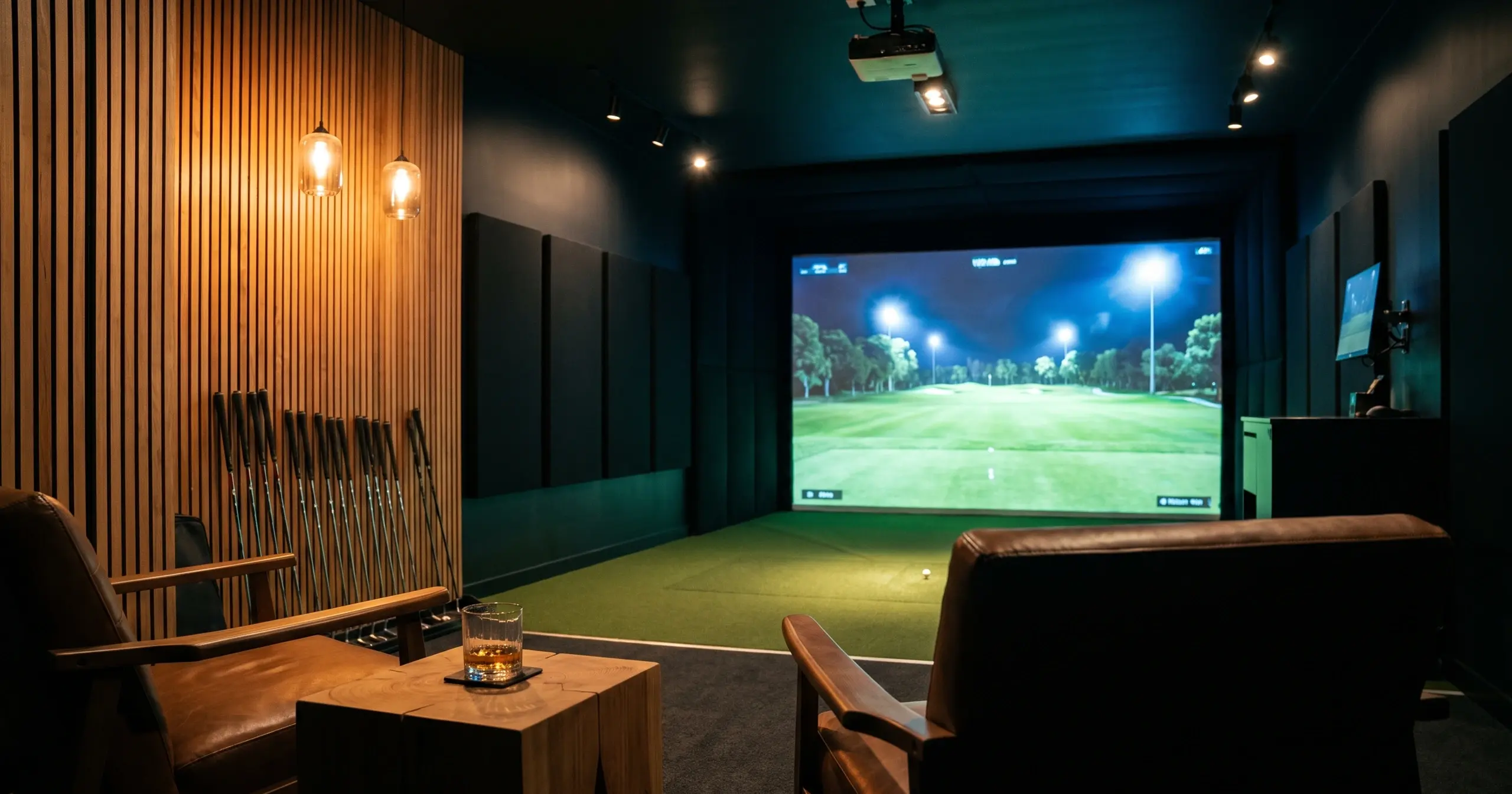 Warmly lit studio lounge with a golf simulator screen glowing at one end and lounge seating alongside
